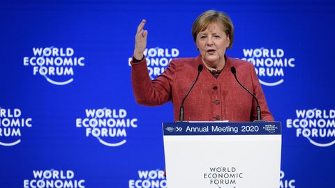 Bundeskanzlerin Merkel steht auf dem Podium vor einer blauen Wand mit "World Economic Forum"-Logo und gestikuliert