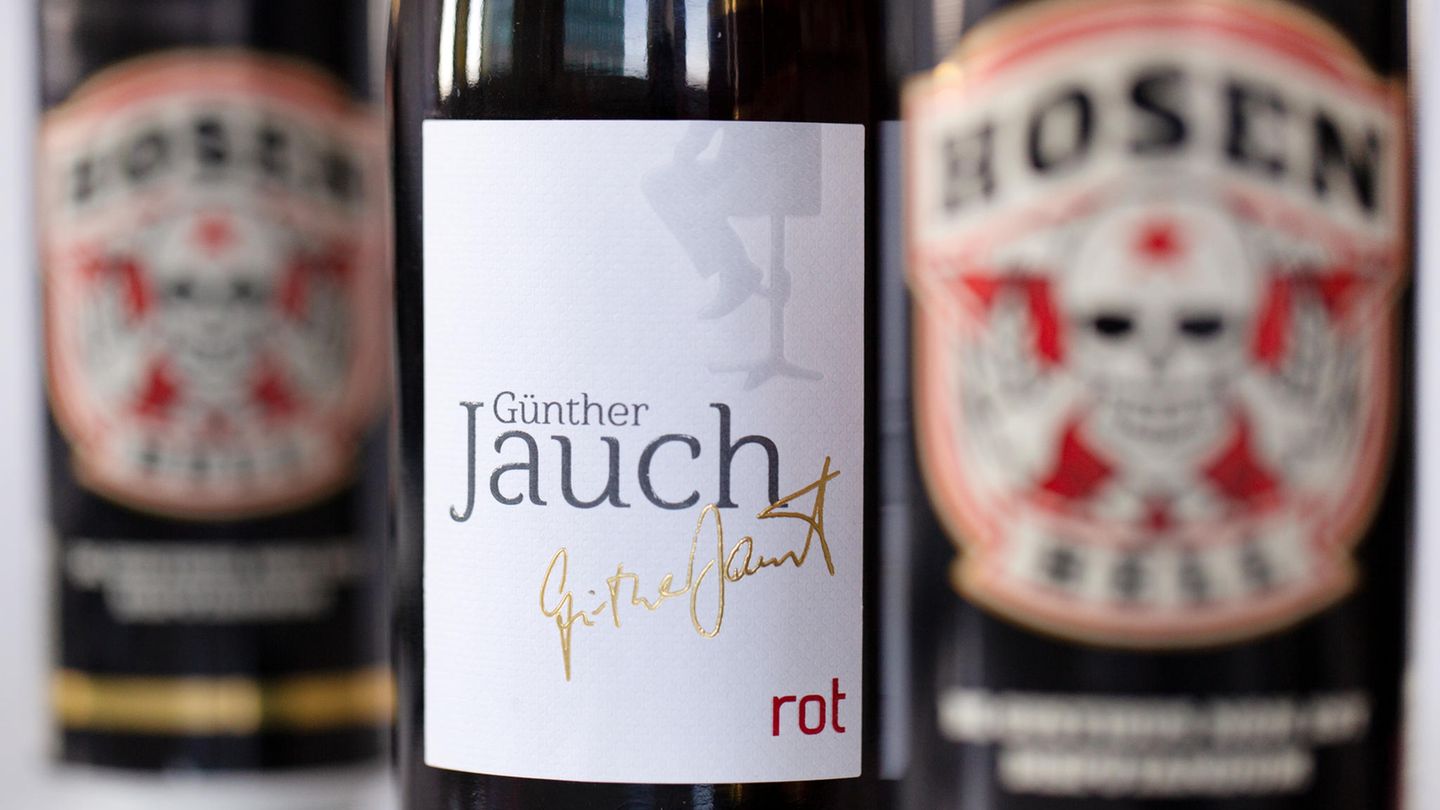 Eine Flasche Wein "Günther Jauch" steht zwischen Bierdosen "Hosen Hell" von der Band "Die Toten Hosen". Beide Produkte werden in einem Discounter verkauft.