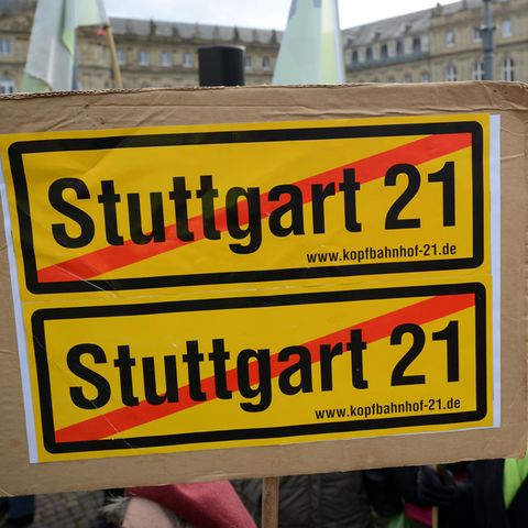 Eine Frau hält bei einer Demo im Jahre 2012 ein durchgestrichenes Stuttgart21-Plakat vor dem Finanzministerium im Neuen Schloss in Stuttgart in die Höhe