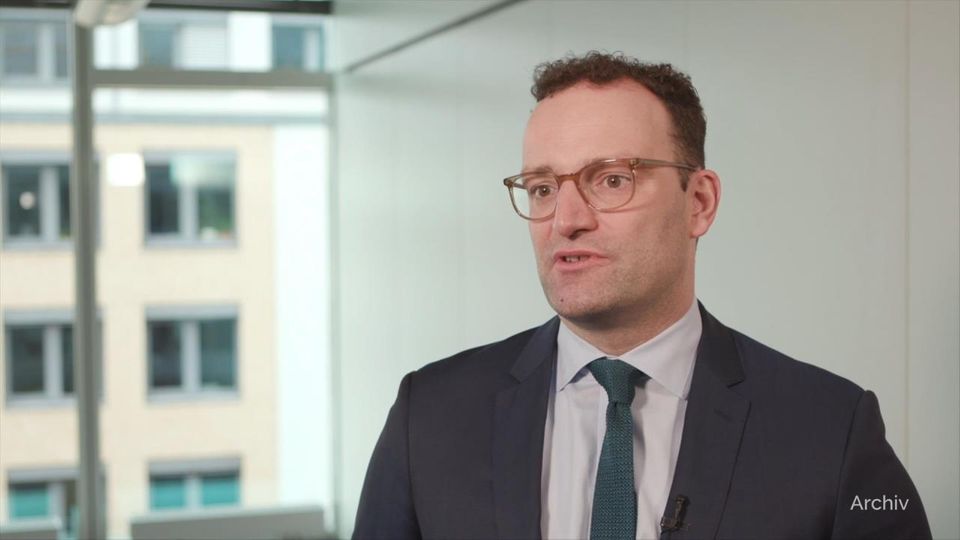 Bundesgesundheitsminister Jens Spahn Ein Mann im dunklen Anzug und petrolfarbener Krawatte sitzt in einem Raum mit weiß gestrichenen Wänden
