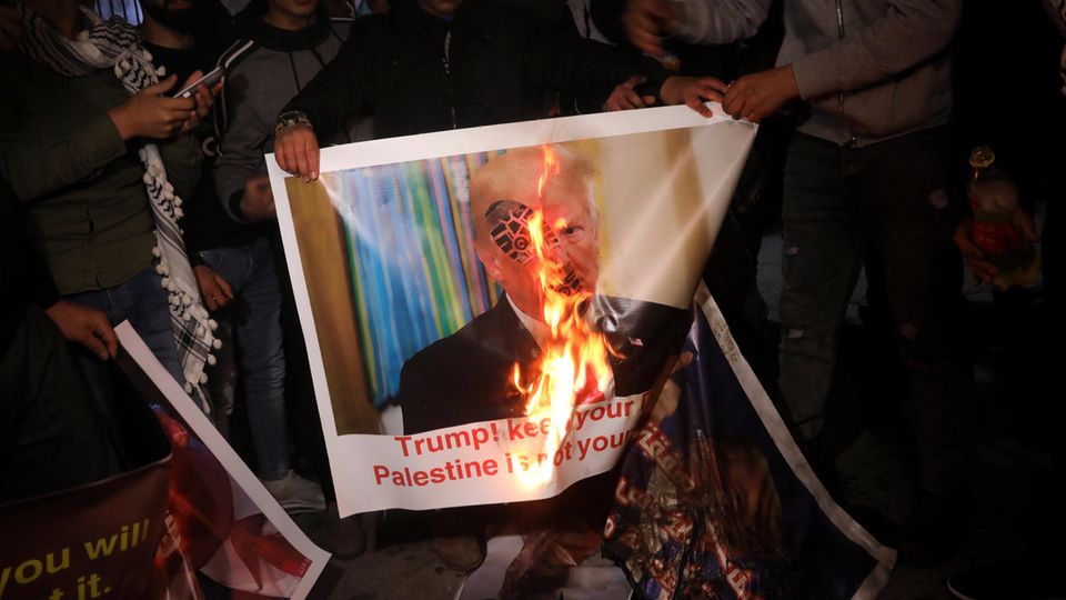Demonstranten verbrennen ein Plakat mit dem Bild Donald Trumps