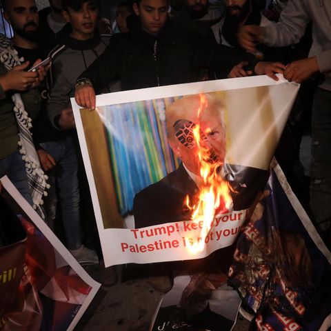 Demonstranten verbrennen ein Plakat mit dem Bild Donald Trumps