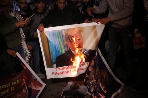 Demonstranten verbrennen ein Plakat mit dem Bild Donald Trumps