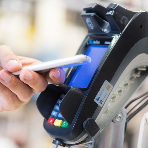 Ein Mann bezahlt in einem Laden in Berlin mit seinem Smartphone