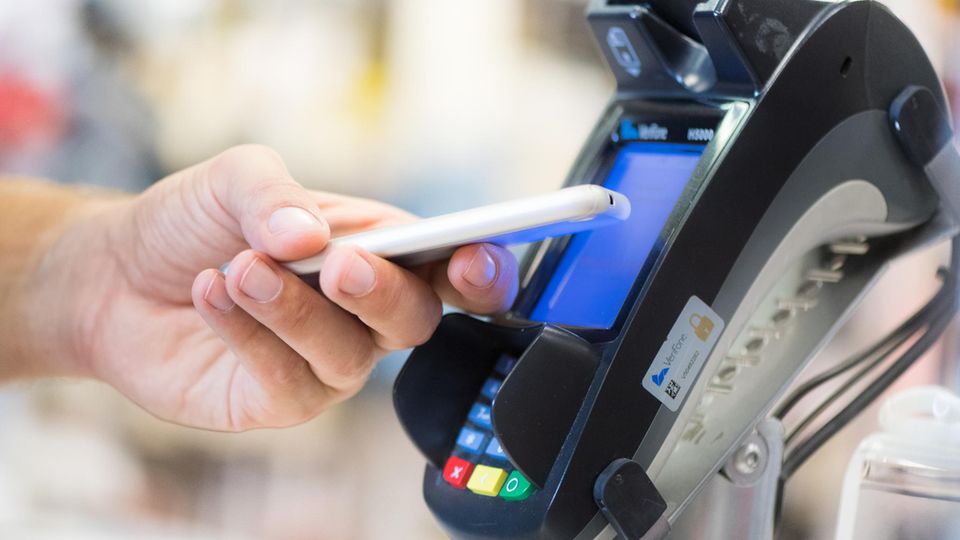 Ein Mann bezahlt in einem Laden in Berlin mit seinem Smartphone
