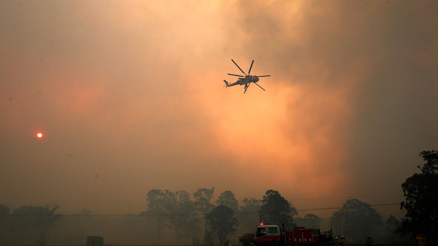 Ein Hubschrauber wirft Wasser auf ein außer Kontrolle geratenes Feuer