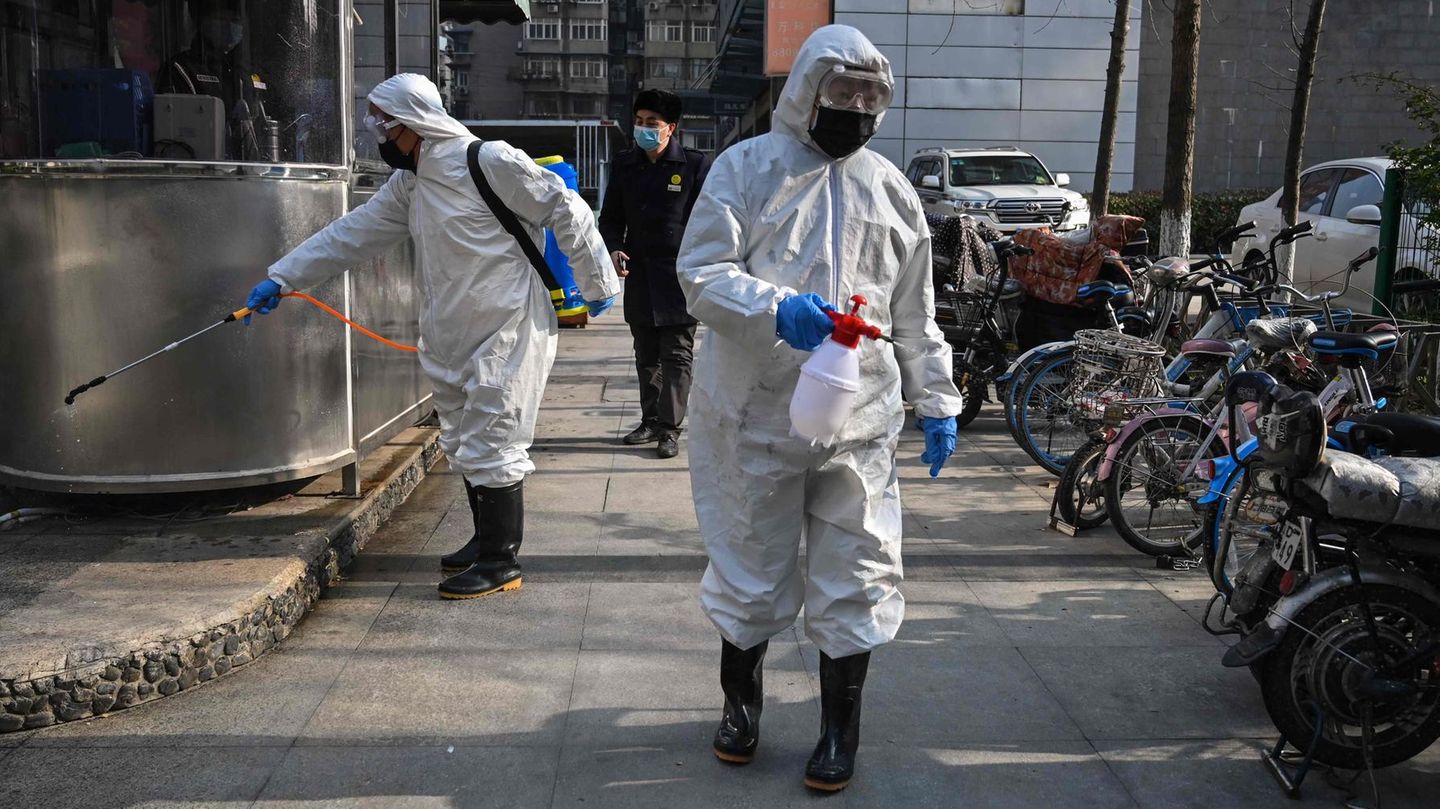 Auf den Straßen von Wuhan versprühen zwei Menschen Desinfektionsmittel
