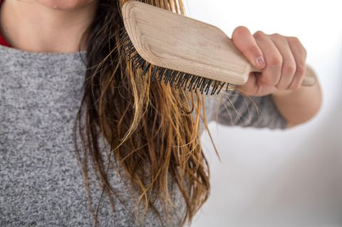 Fettige Haare: Frau kämmt sich mit einer Bürste ihre langen Haare