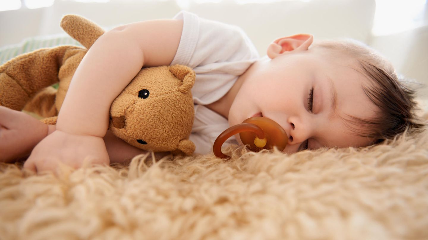 Ein Baby liegt schlafend auf einem Schaffell