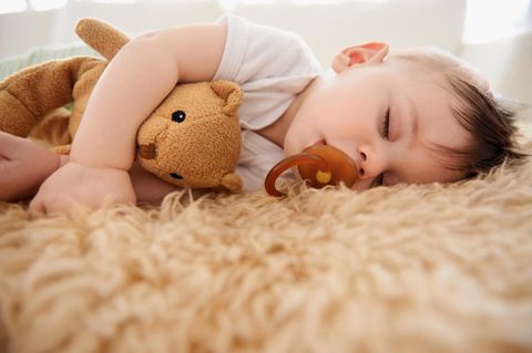 Ein Baby liegt schlafend auf einem Schaffell