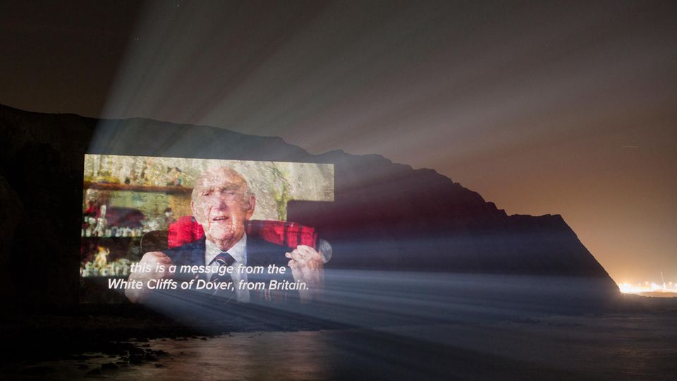 Projektion Bei Nacht sind nur die Konturen der Klippen von Dover zu sehen. Darauf die Projektion eines alten Mannes im Anzug