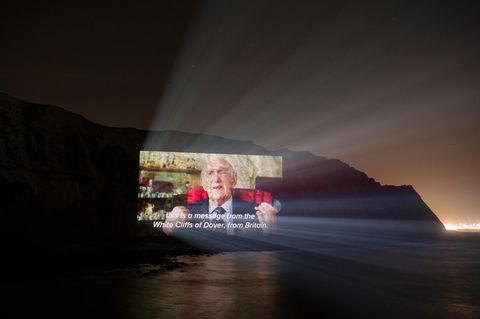 Bei Nacht sind nur die Konturen der Klippen von Dover zu sehen. Darauf die Projektion eines alten Mannes im Anzug