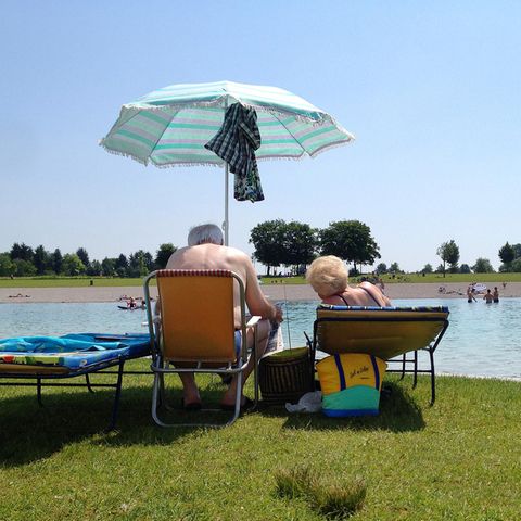 Senioren auf Sonnenliegen mit Sonnenschirm