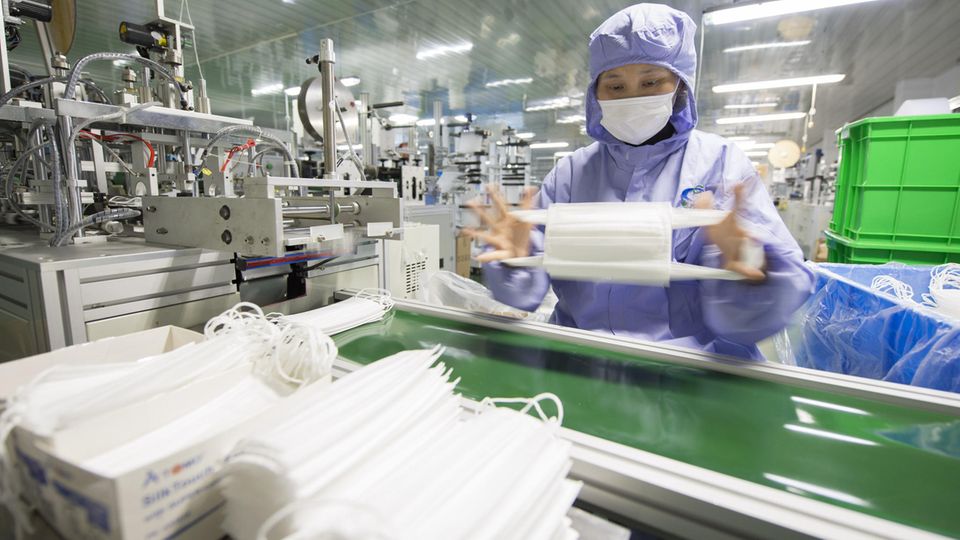 Eine Arbeiterin überprüft Atemschutzmasken in einer Fabrik im Osten Chinas