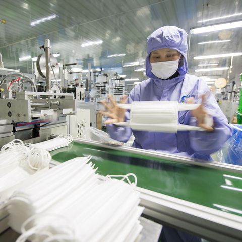 Eine Arbeiterin überprüft Atemschutzmasken in einer Fabrik im Osten Chinas