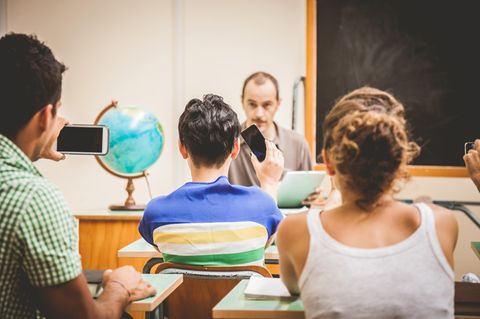 Ein Lehrer wird von zwei Schülern im Klassenraum per Handy gefilmt