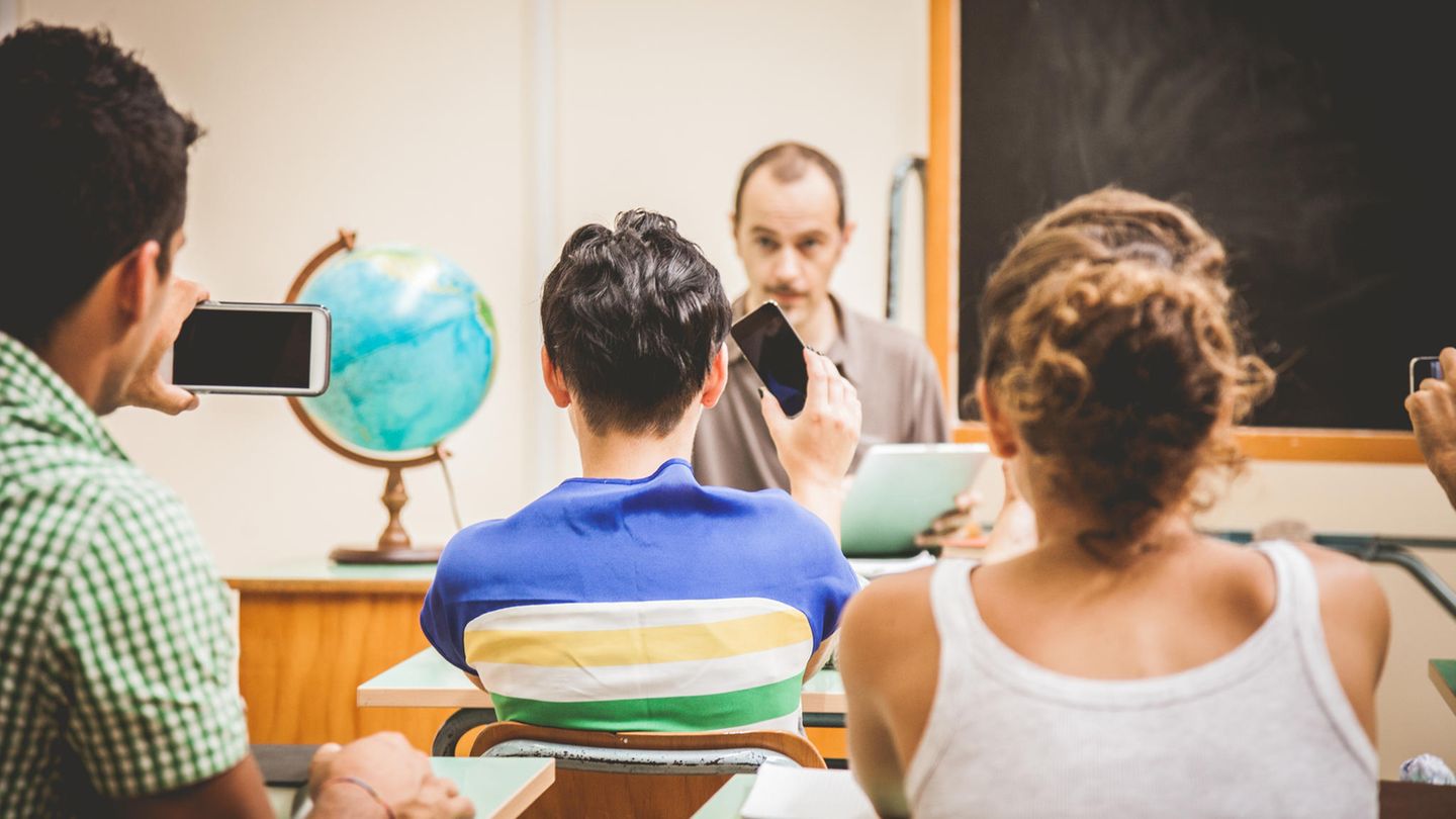 Ein Lehrer wird von zwei Schülern im Klassenraum per Handy gefilmt