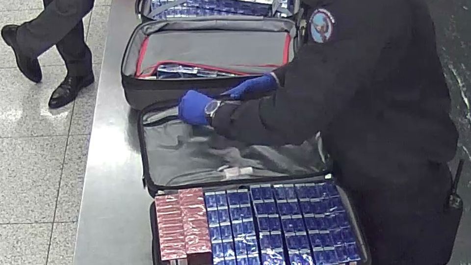 Ein Zollbeamter kontrolliert die Reisekoffer des Mannes mit den Zigaretten