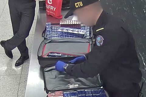 Ein Zollbeamter kontrolliert die Reisekoffer des Mannes mit den Zigaretten