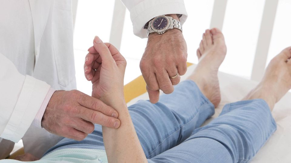 Puls messen: Ein Arzt misst per Hand und Armbanduhr den Puls einer Patientin