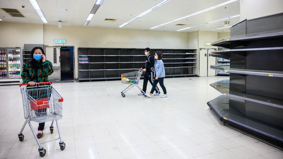 Hongkong: Käufer mit Schutzmasken gehen an leeren Supermarktregalen vorbei,