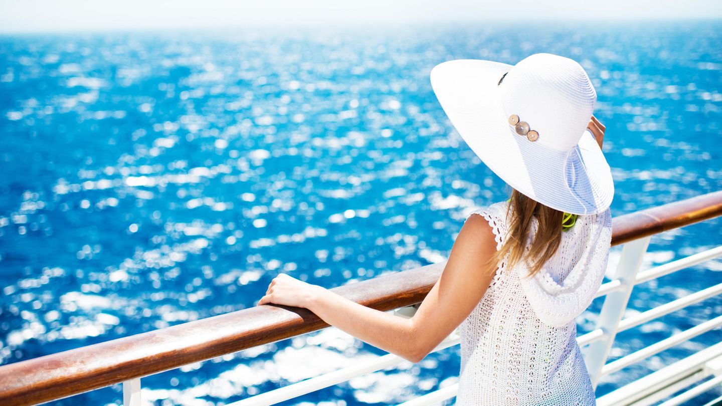 Eine Frau steht an der Reling eines Kreuzfahrtschiffes