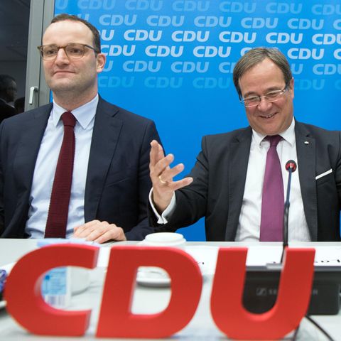 Vor einer blauen Wand mit helleren CDU-Logos sitzen drei Männer mit Anzügen und Krawatten an einem Tisch mit Mikrofonen