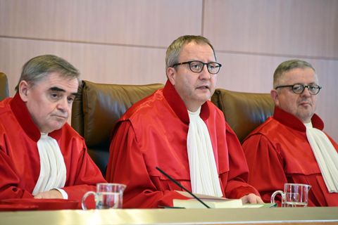 Drei Männer in roten Roben sitzen nebeneinander auf der Richterbank