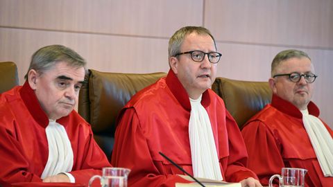 Drei Männer in roten Roben sitzen nebeneinander auf der Richterbank