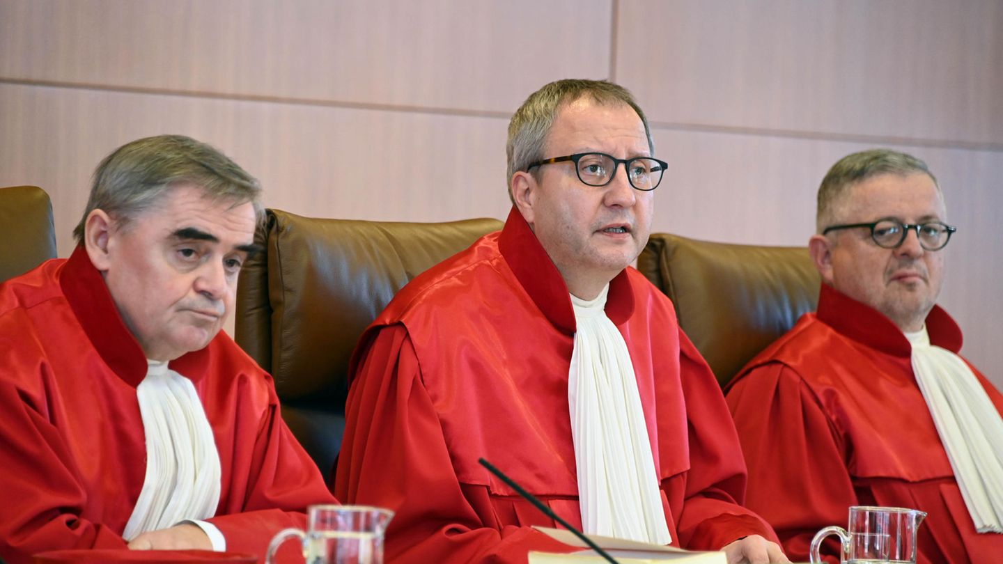 Drei Männer in roten Roben sitzen nebeneinander auf der Richterbank