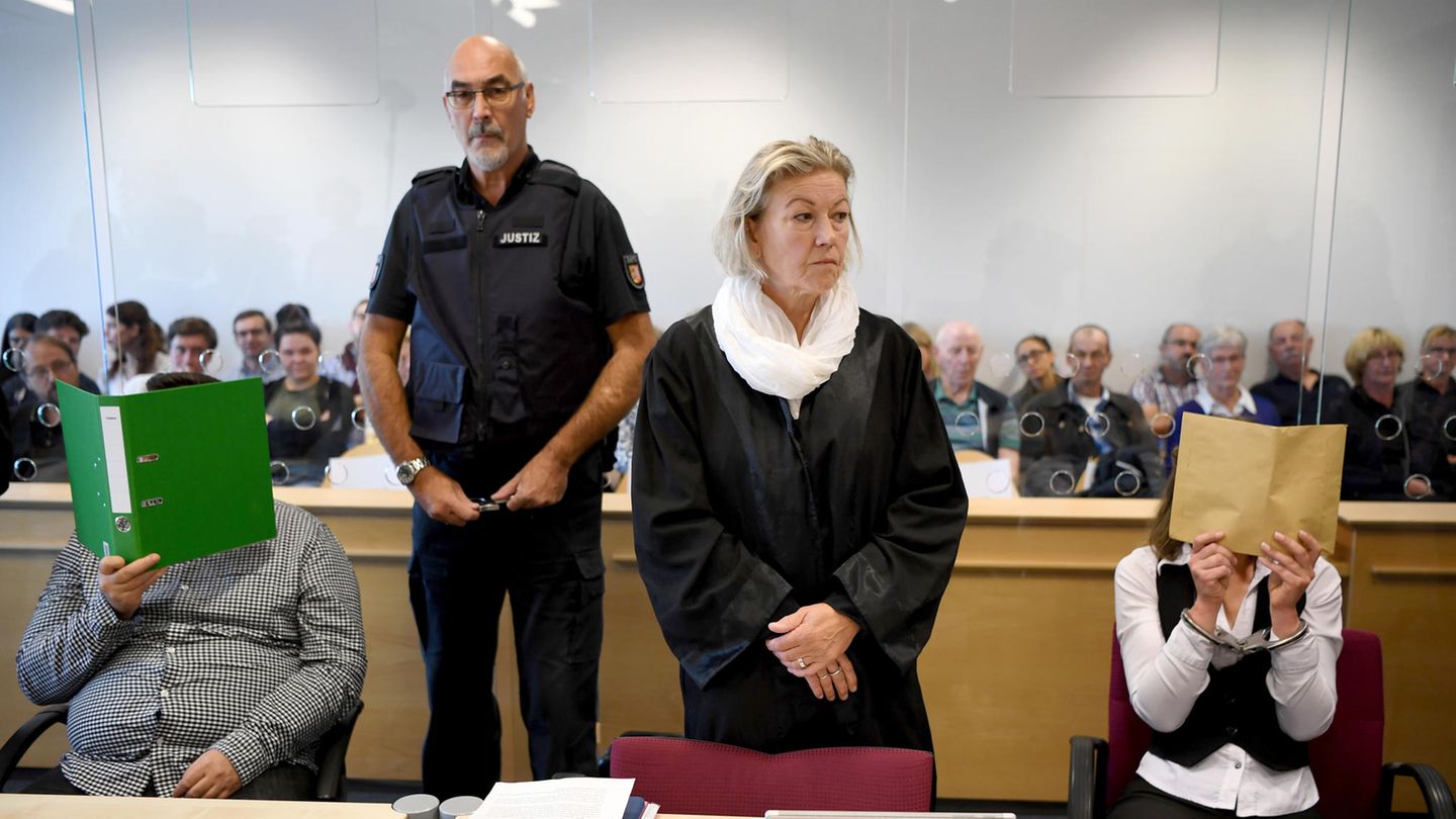 Ein Foto vom Prozessauftakt im vergangenen August: Die beiden Angeklagten verdecken ihre Gesichter