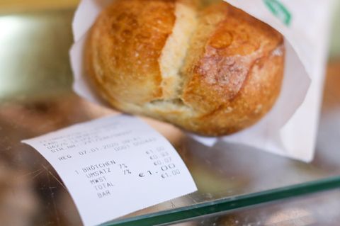 Ein Kassenbon liegt neben einem Brötchen