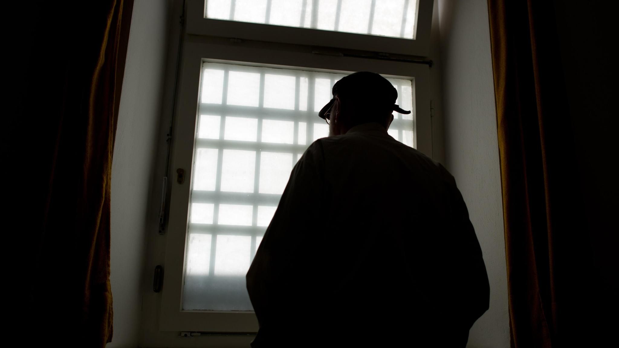 Mann vor vergittertem Gefängnisfenster