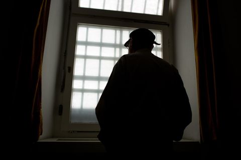 Mann vor vergittertem Gefängnisfenster