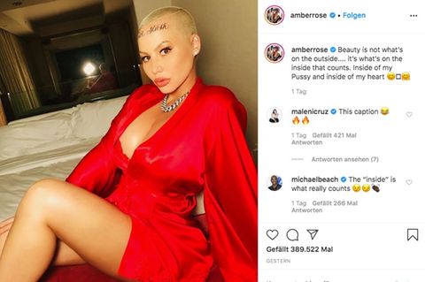 Model Amber Rose in einem weit ausgeschnittenen roten Kleid und mit einem Tattoo auf der Stirn