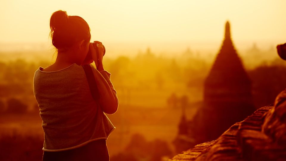 Eine Frau fotografiert eine Tempelanlage in Myanmar