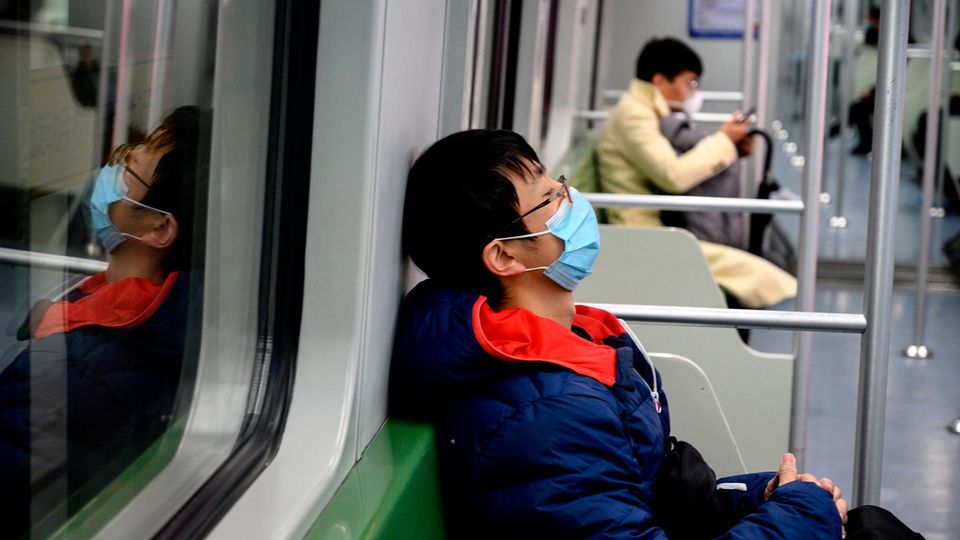 Leere U-Bahn in Shanghai mit zwei Atemmasken tragenden Fahrgästen