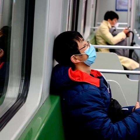Leere U-Bahn in Shanghai mit zwei Atemmasken tragenden Fahrgästen