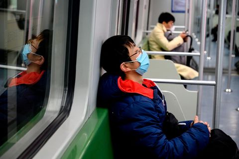 Leere U-Bahn in Shanghai mit zwei Atemmasken tragenden Fahrgästen