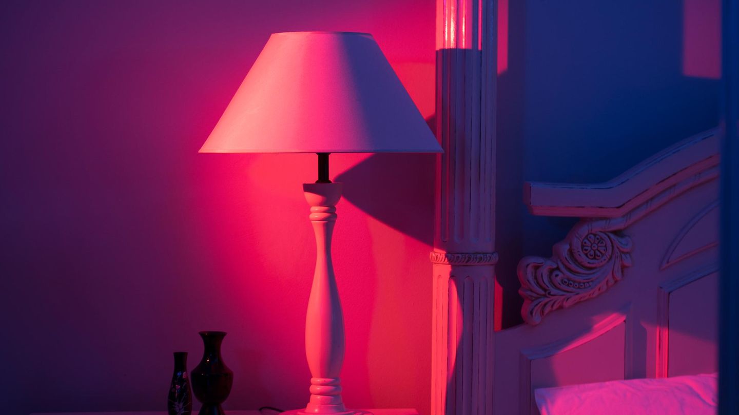Lampe steht im Rotlicht neben einem Bett