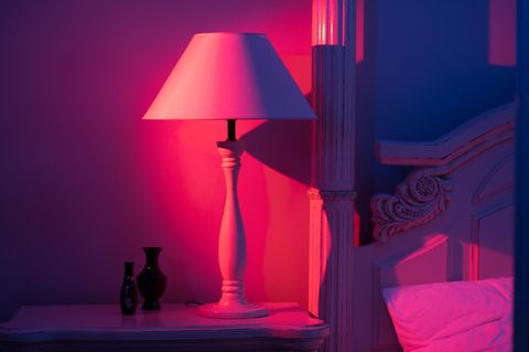 Lampe steht im Rotlicht neben einem Bett