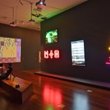 Video- und Neonkunst im Ian Potter Centre in Melbourne: In der Mitte oben ein grünes Neon-Emu auf dem Union Jack: "dhalaay yuulay - passionate skin" und rechts die gelben Neon-Schlagstöcke "Buuga-Buuga", beides Installationen von Brook Andrew.
