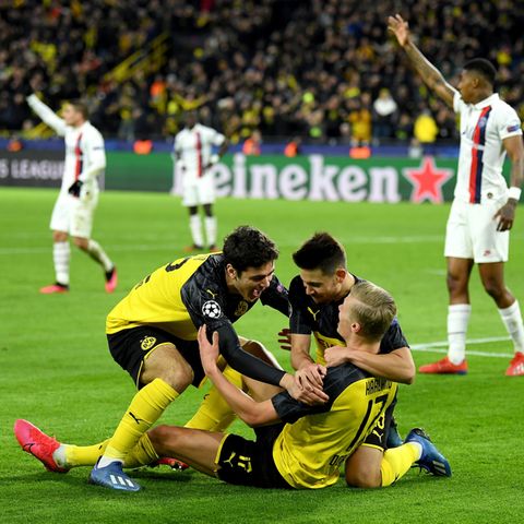 Drei Dortmunder Spieler jubeln auf den Rasen, während PSG-Spieler konsterniert im Hintergrund stehen