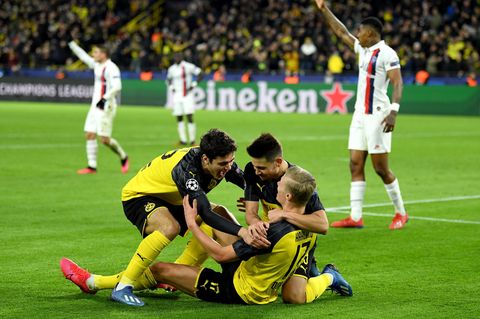 Drei Dortmunder Spieler jubeln auf den Rasen, während PSG-Spieler konsterniert im Hintergrund stehen