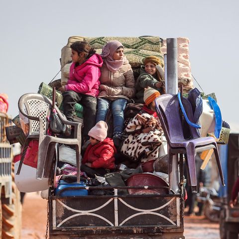 Kinder sitzen auf der Ladefläche eines Kleintransporters auf den Habseligkeiten ihrer Familie