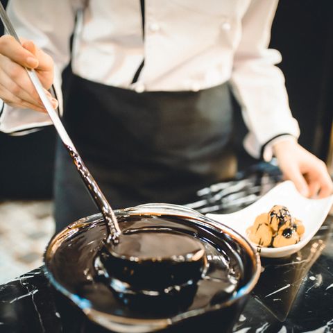 Ein Koch schöpft Schokoladensauce aus einem Topf