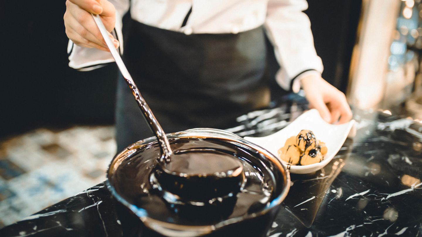 Ein Koch schöpft Schokoladensauce aus einem Topf