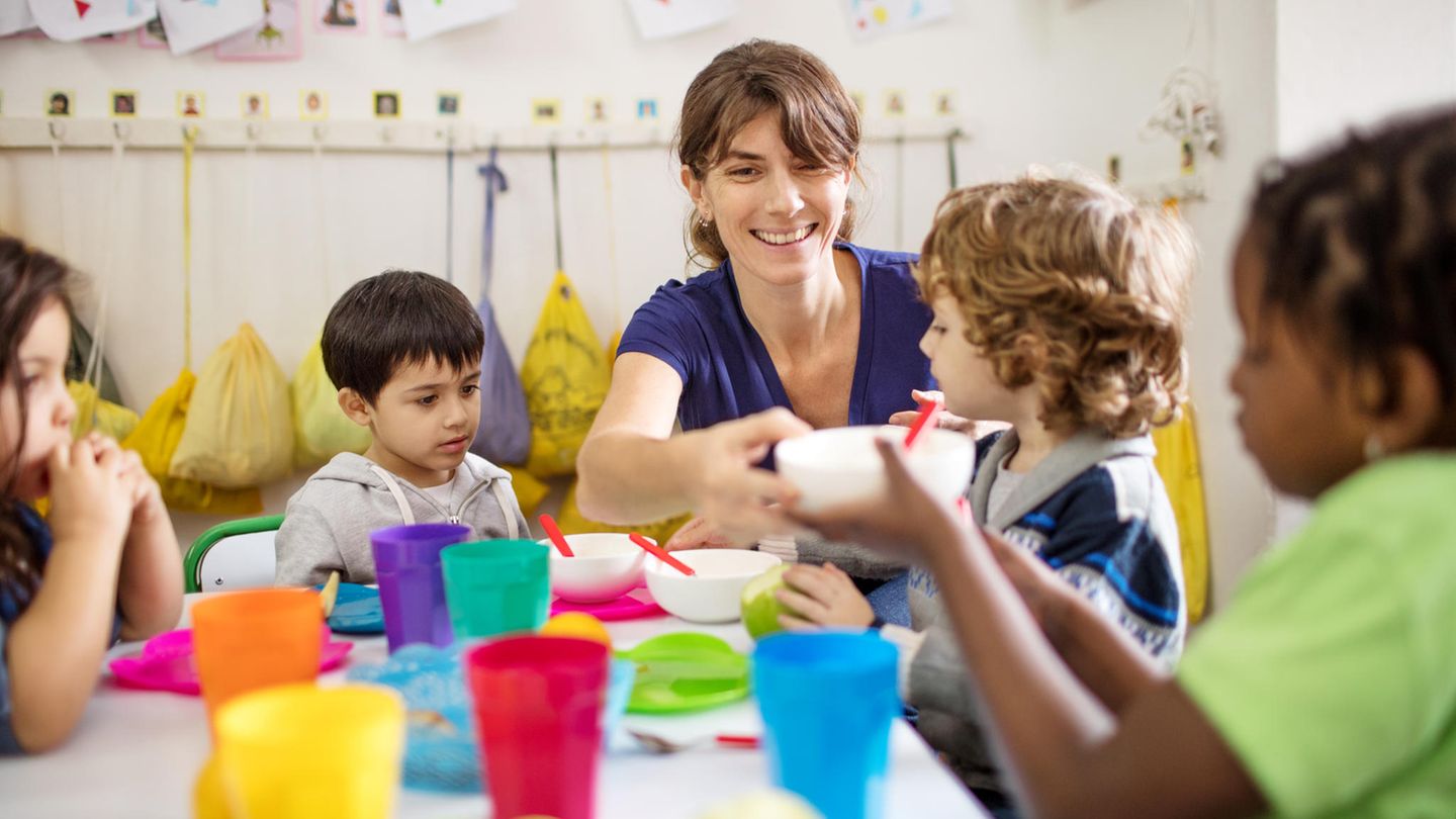 Erzieherin mit Kindern beim Essen