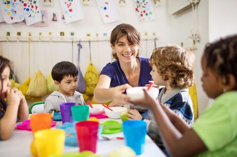 Erzieherin mit Kindern beim Essen