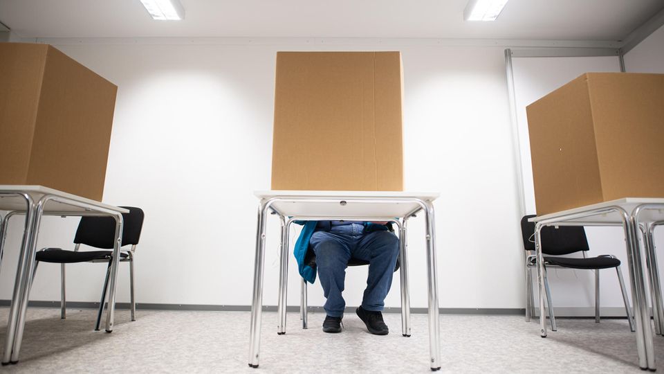 Hamburg: Ein Mann gibt in einer Wahlkabine seine Stimme ab.